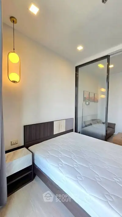 Modern bedroom with sleek design and large glass sliding door, featuring a stylish pendant light.