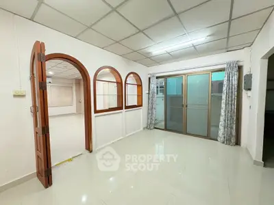 Spacious living room with modern tile flooring and sliding glass doors leading to a balcony.