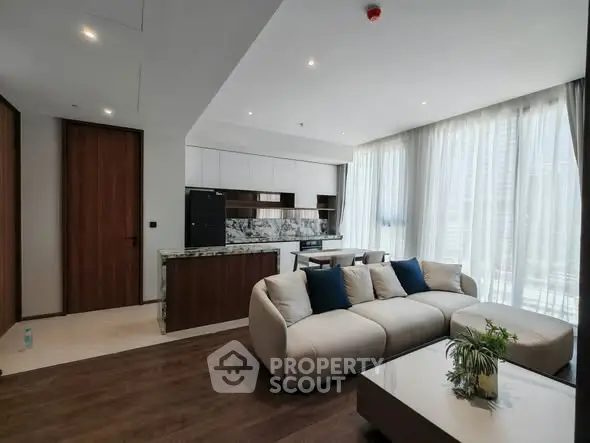 Modern open-layout living room with stylish kitchen and large windows