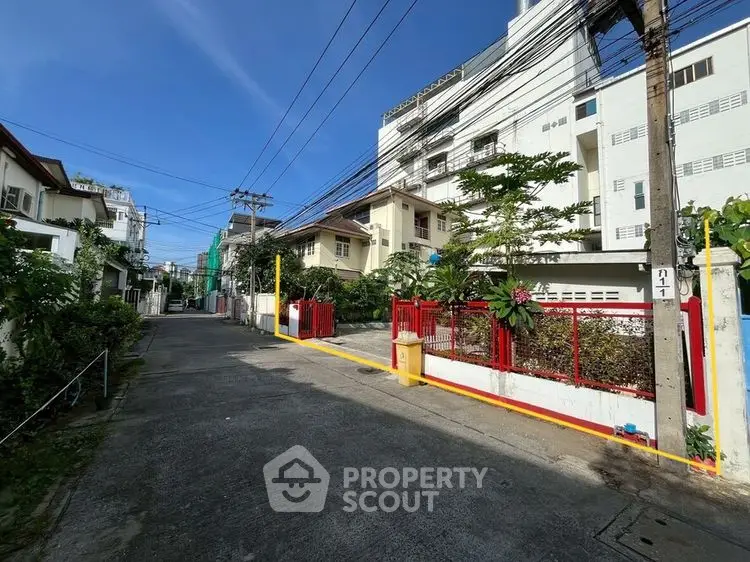 Charming residential street with modern buildings and lush greenery under a clear blue sky.