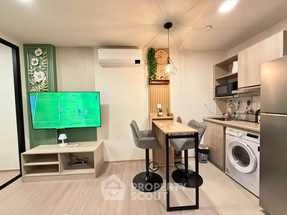 Modern living room with stylish decor, open kitchen, and built-in appliances including washing machine and fridge.