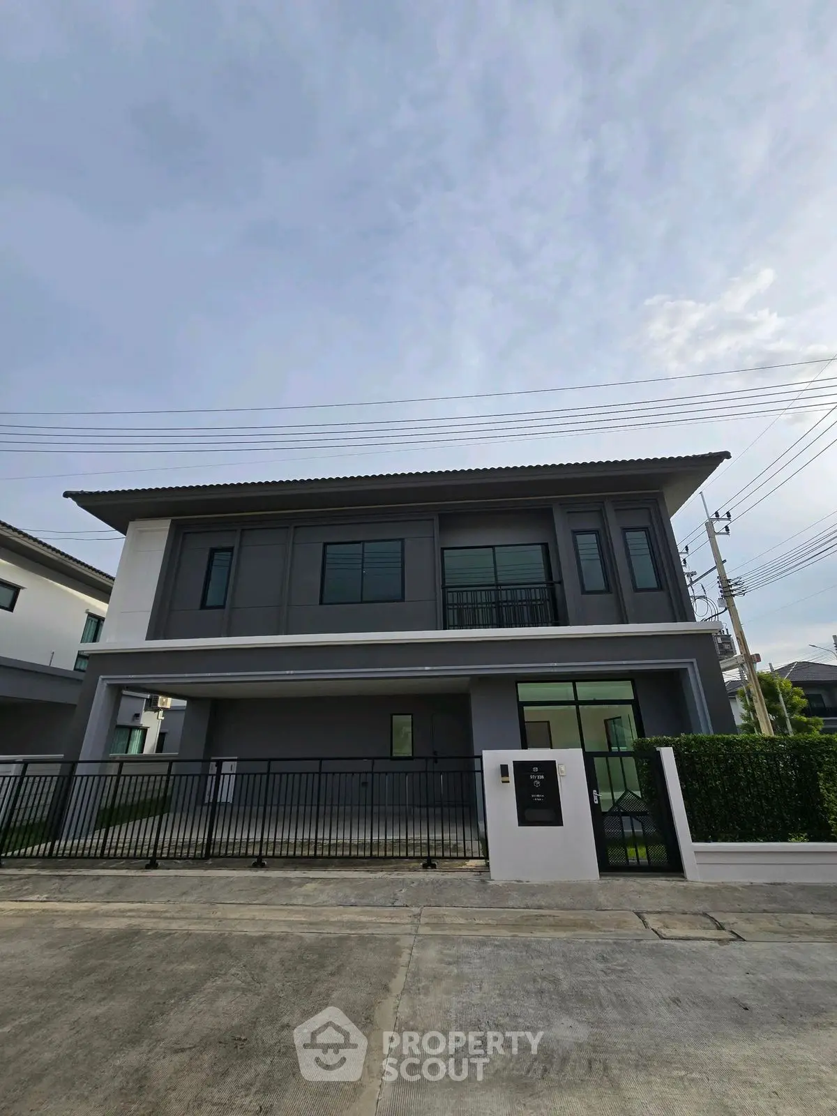 Modern two-story house with sleek design and gated entrance in suburban neighborhood.