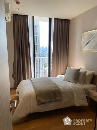 Modern bedroom with city view, featuring cozy bed and elegant decor.