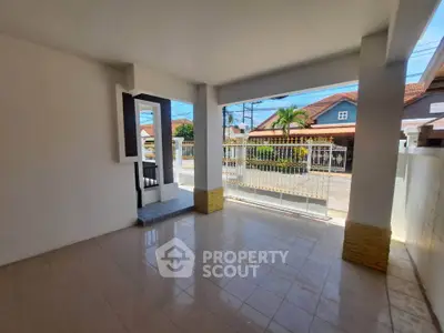 Spacious covered patio with tiled flooring and street view, perfect for outdoor relaxation.