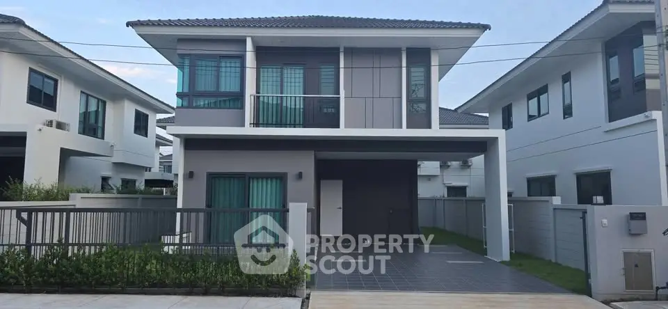 Modern two-story house with sleek design and spacious driveway in a suburban neighborhood.