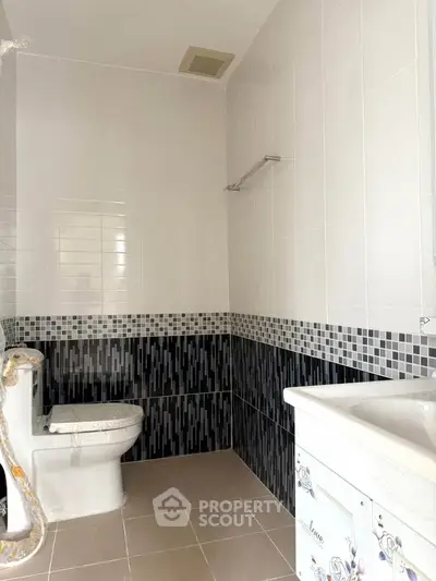 Modern bathroom with stylish black and white tile design and sleek fixtures.