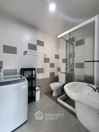 Modern bathroom with washing machine and shower in stylish apartment.