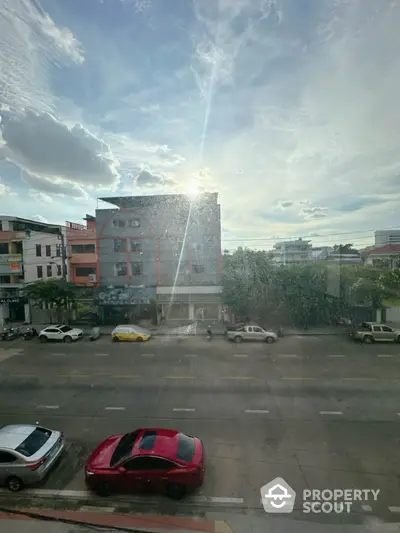 Urban street view with residential buildings and parked cars under a bright sky