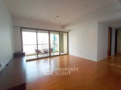 Spacious living room with wooden flooring and large balcony offering city views.