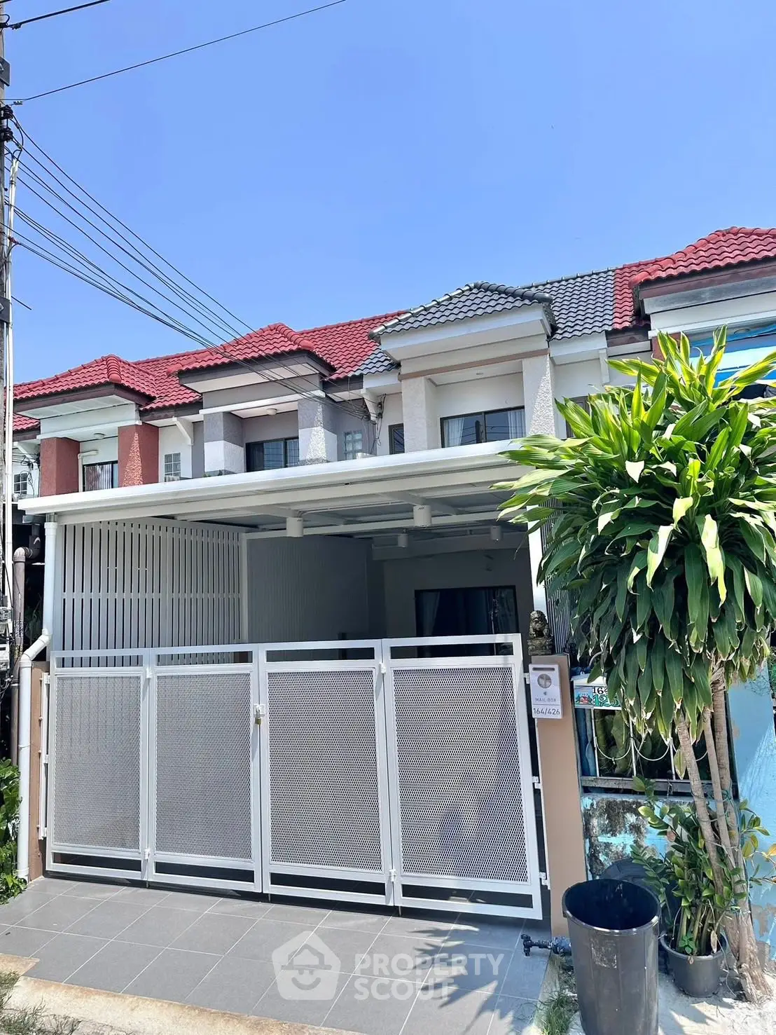Charming townhouse with modern facade and gated entrance in a serene neighborhood.