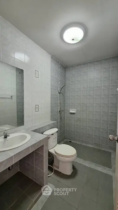 Spacious bathroom with modern fixtures and tiled walls, featuring a shower and vanity.