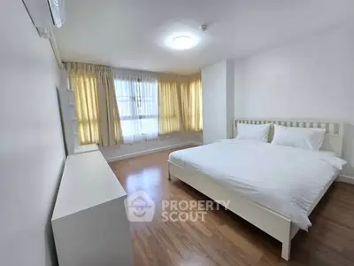 Spacious bedroom with natural light and elegant wooden flooring