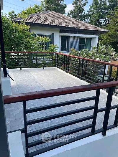 Spacious balcony with modern railing and lush greenery view, perfect for outdoor relaxation and entertainment.