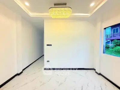Elegant interior with modern chandelier and marble flooring in a bright room with garden view.
