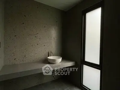 Minimalist bathroom with stone wall and frosted window