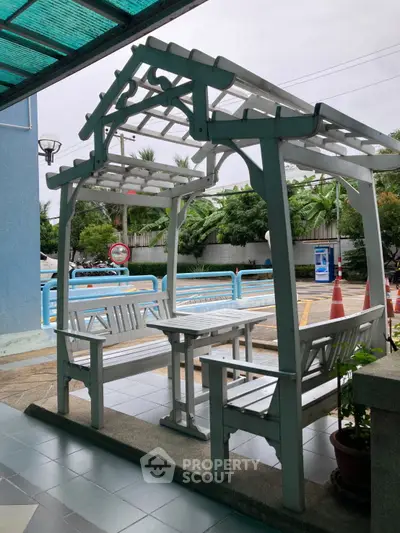 Charming outdoor seating area with white pergola and benches, perfect for relaxation in a serene garden setting.