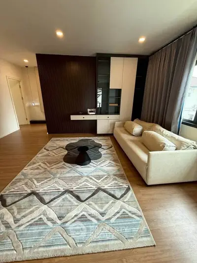Spacious living room with modern decor and large rug, perfect for relaxation.