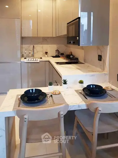 Modern kitchen with sleek cabinetry and marble countertops, featuring a cozy dining area for two.