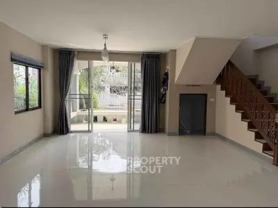 Spacious living room with large windows and elegant staircase