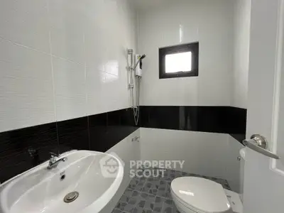 Modern bathroom with sleek design, featuring a shower, sink, and toilet in a compact space.