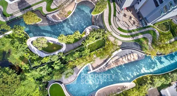 Stunning aerial view of modern residential complex with lush gardens and winding water features.