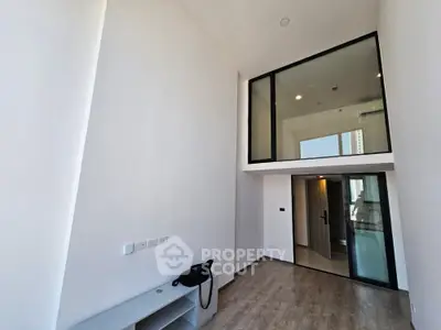 Modern minimalist studio apartment with high ceilings, large mirror, and sleek finishes, perfect for urban living.