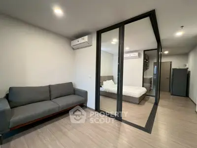 Modern apartment with glass partition, cozy living room, and sleek bedroom design.