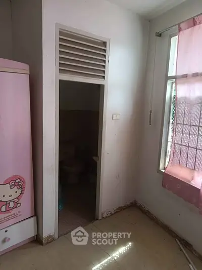 Cozy bedroom with pink decor and attached bathroom, perfect for a child's room.
