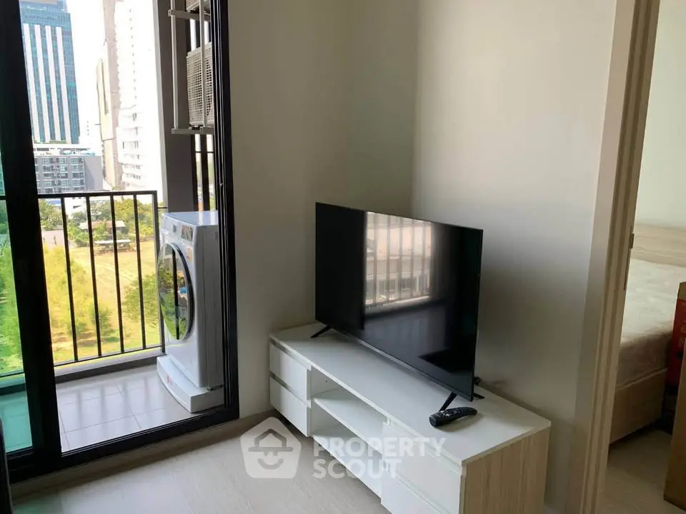 Modern apartment with balcony view, featuring sleek TV setup and washing machine for urban living.