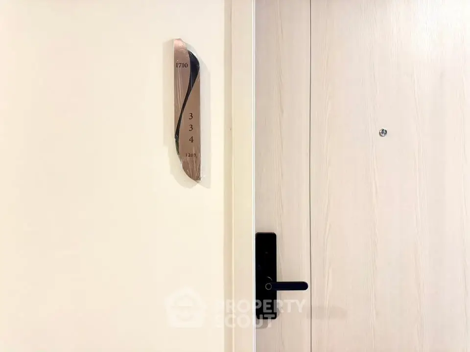 Modern apartment entrance with sleek door and room number signage, showcasing contemporary design.