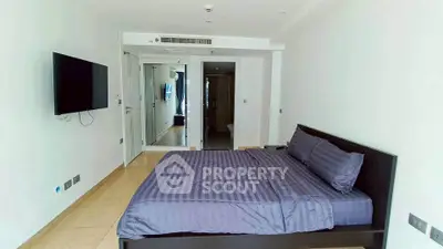 Spacious modern bedroom with sleek design and wall-mounted TV in a contemporary apartment.