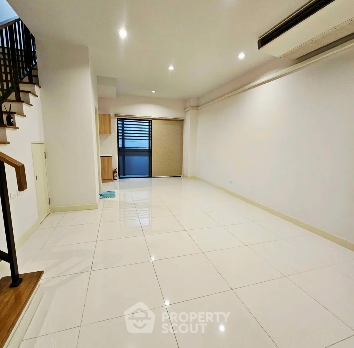 Spacious modern living room with sleek tile flooring and staircase.