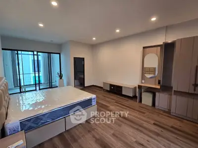 Spacious modern bedroom with elegant wooden flooring and large windows for natural light.