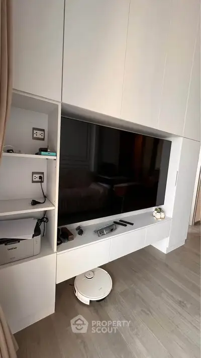 Modern living room with built-in TV unit and smart vacuum on wooden floor