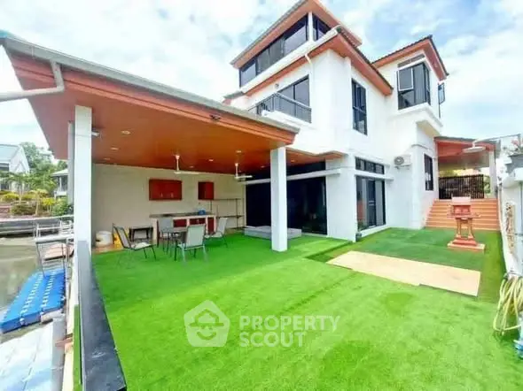 Stunning modern waterfront home with spacious outdoor area and lush artificial grass.