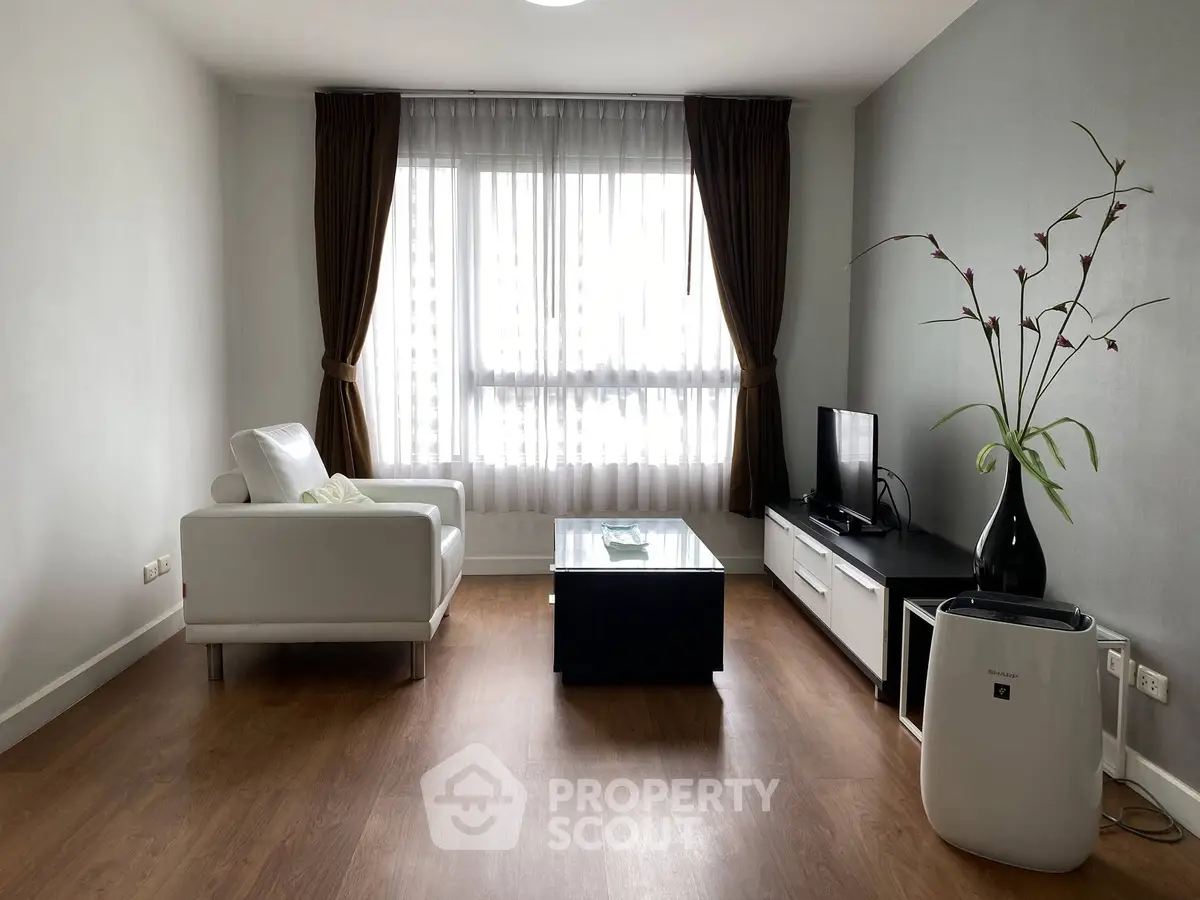 Modern living room with sleek furniture and large window, perfect for relaxation and entertainment.