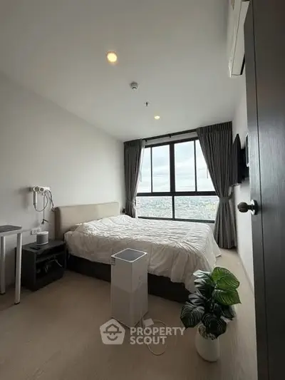 Modern bedroom with large window offering stunning city view, stylish decor, and cozy ambiance.