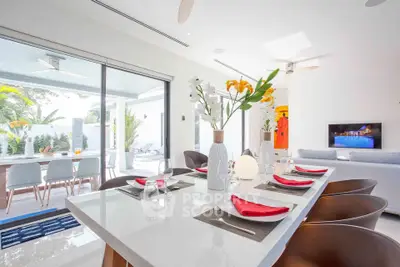 Luxurious open-plan living and dining area with modern decor and poolside view.