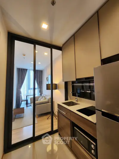 Modern kitchen with sleek design and open layout leading to a cozy living room with natural light.