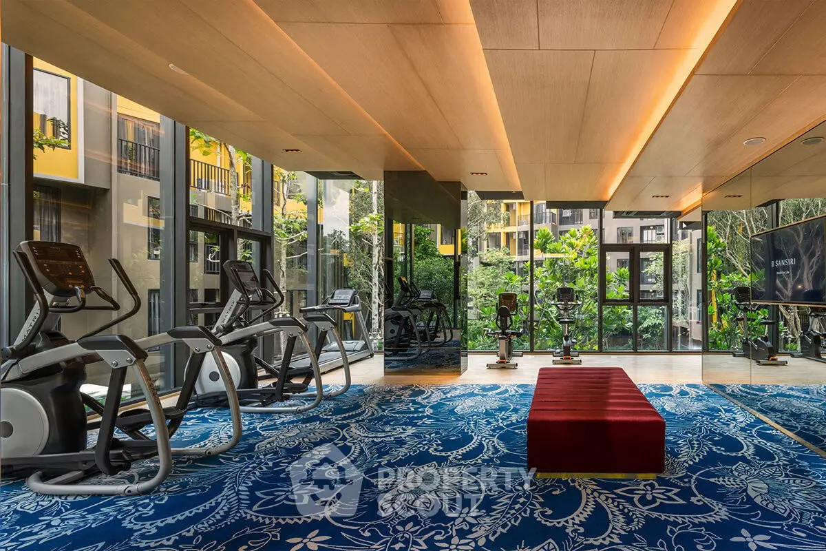 Luxurious gym with modern equipment and scenic garden views in upscale residential building.