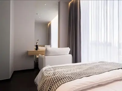 Modern bedroom with elegant decor and large window with sheer curtains.