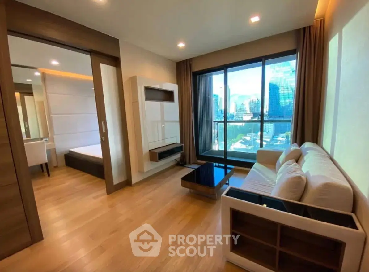 Modern living room with large windows and city view, featuring sleek furniture and wooden flooring.