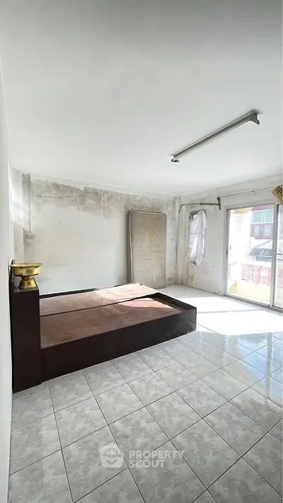 Spacious bedroom with natural light and tiled flooring, featuring a minimalist design.