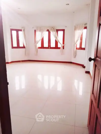 Spacious empty room with large windows and white tiled floor, perfect for customization.