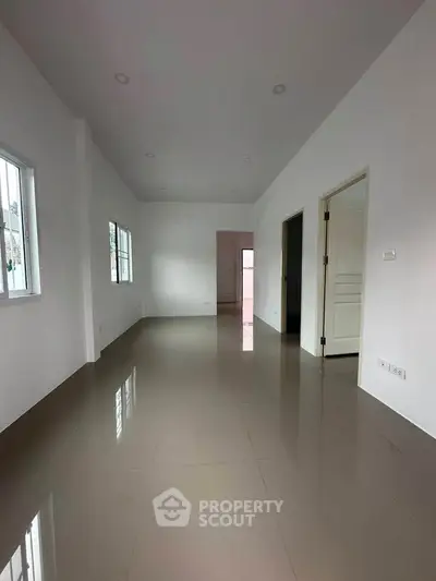 Spacious empty room with glossy tiled floors and white walls, ideal for customization.