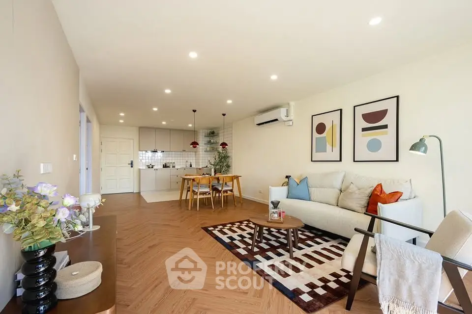 Spacious modern living room with open kitchen, stylish decor, and elegant lighting.