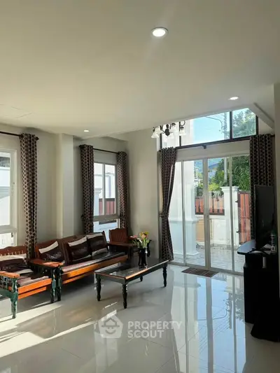 Spacious living room with elegant wooden furniture and large windows offering natural light.