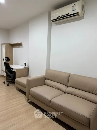 Modern living room with beige sofa and study desk, featuring air conditioning.