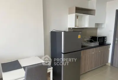 Modern kitchen with sleek appliances and dining area in contemporary apartment.