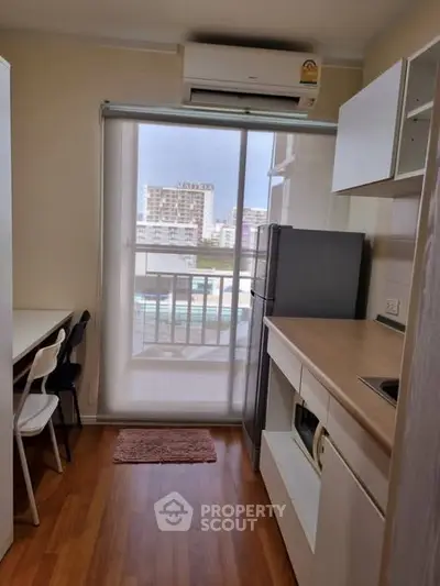 Modern kitchen with balcony view, featuring sleek cabinetry and hardwood floors.